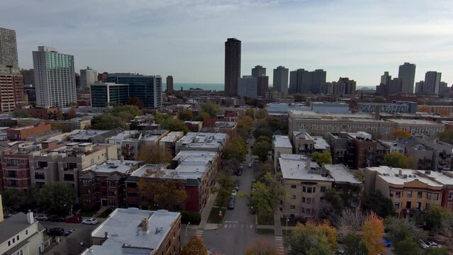 panning aerial footage of an autumn landscape in Chicago with skyscrapers and office buildings in the city skyline, railroad tracks, trains, autumn trees and cars driving on the street in Illinois USA
