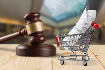 Shopping cart and wooden judge gavel on table