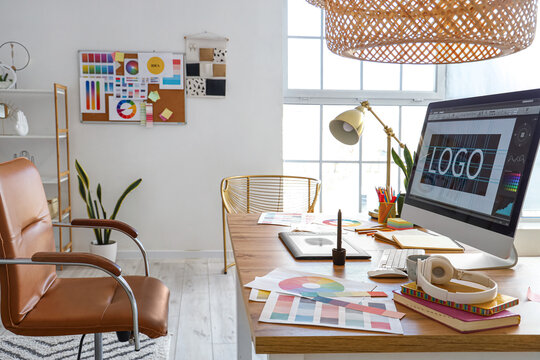 Graphic designer's workplace with computer, tablet and paint palettes in office