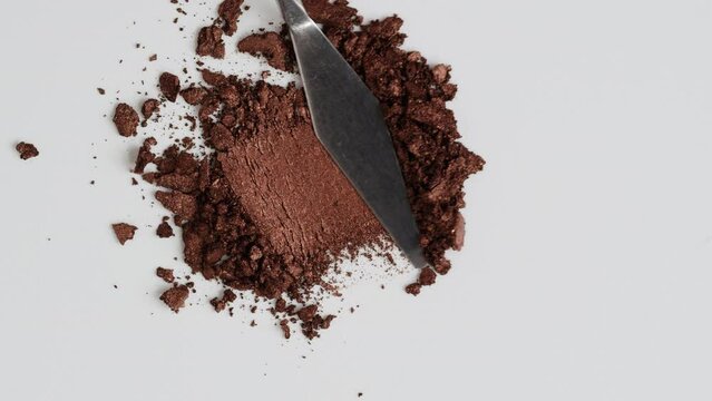 Broken by knife brown smashed make up eyeshadow pallete, lay of brush strokes on white desk, close-up for beauty shop background, top colorful view, Sample cosmetics concept.
