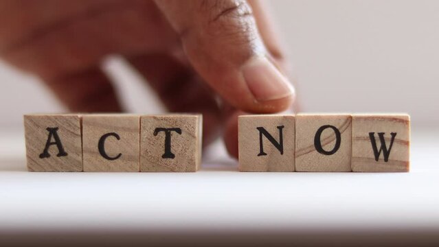 Hand comes in and spells the word ACT NOW with block letters