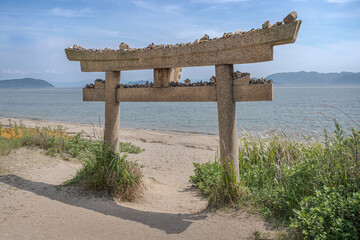Stone torii with stone pebbles left by visitors.
The Shinto gate symbol that marks the transition...