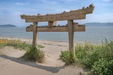 Fotobehang Stone torii with stone pebbles left by visitors. The Shinto gate symbol that marks the transition from the mundane to the sacred.  © LRafael