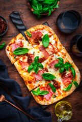 Rectangular roman pizza with smoked ham, mozzarella cheese, sun dried tomatoes, tomato sauce and...
