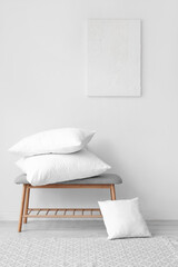Fototapeta na wymiar Grey bench with pillows near white wall
