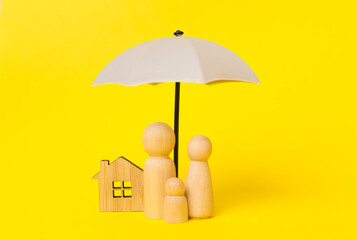 Wooden family figures under umbrella on color background.Insurance coverage concept.