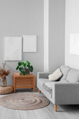 Interior of modern living room with paintings, grey sofa and houseplant