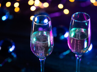 Two champagne glasses on a blue background, a bokeh garland