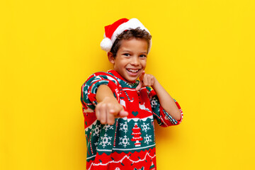 I choose you. african american boy in christmas sweater and santa hat points with his hands forward