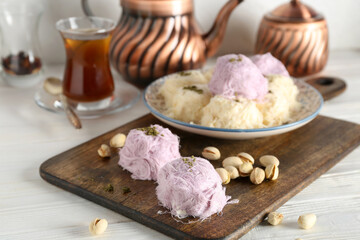 Plate with tasty Turkish Pismaniye and pistachios on table