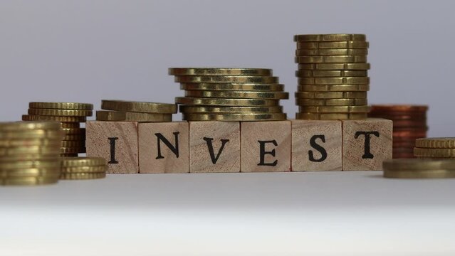 Stop motion video of stacks of coins and block letters spelling the word INVEST