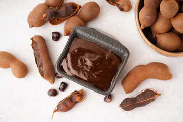 Bowl with tasty tamarind jam with fruits on white background