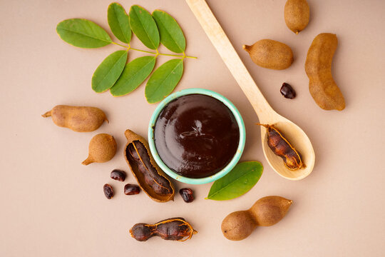 Bowl with tasty tamarind jam with fruits on beige background