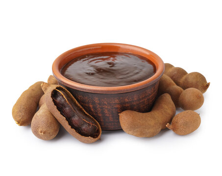 Bowl of tasty tamarind jam and fruits on white background