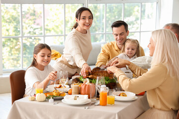 Happy family having dinner at festive table on Thanksgiving Day