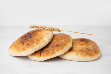 Tasty pita bread and wheat spikelet on white background
