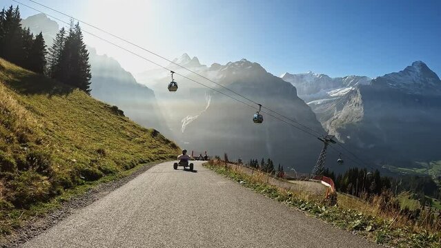 First person view while riding mountain carts on tail in Switzerland under tram in the Alps.