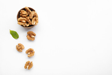 Bowl of tasty walnuts on white background