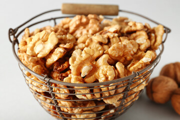 Basket of tasty walnuts on grey background