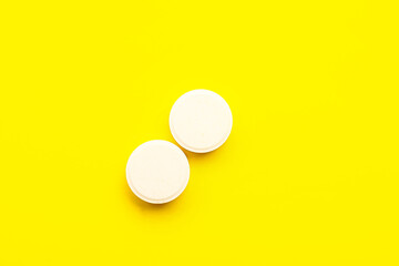 White medical pills on yellow background