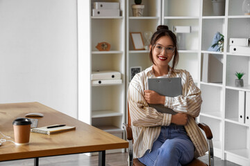 Young Asian businesswoman with clipboard sitting in office