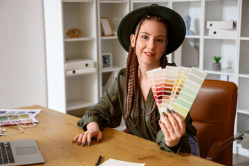 Female designer with color palettes at table in office - obrazy, fototapety, plakaty