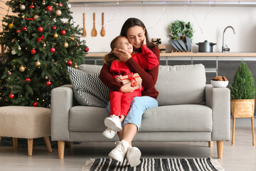 Young mother and her little daughter with Christmas gift at home