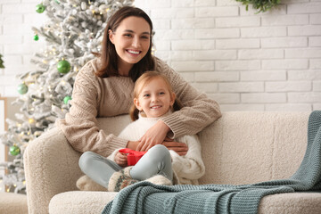 Happy young mother and her little daughter at home on Christmas eve - obrazy, fototapety, plakaty