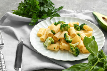 Plate of tasty pasta with broccoli on grey background
