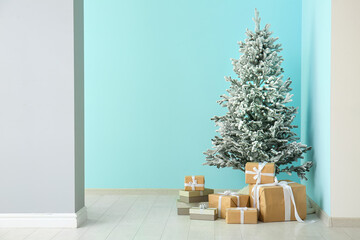 Beautiful Christmas tree with gift boxes near blue wall