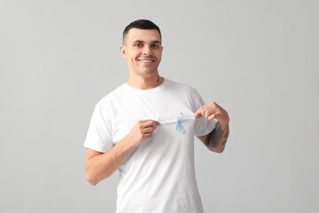 Handsome man with blue ribbon on grey background. Prostate cancer concept