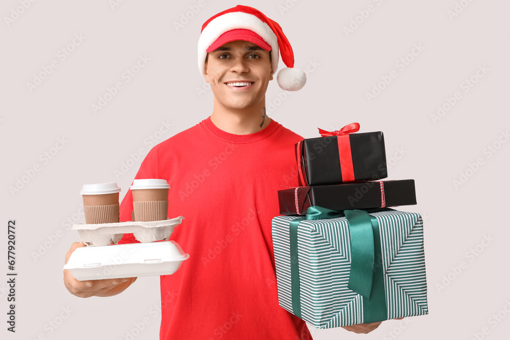 Poster Delivery man in Santa hat with food order, cups of coffee and gift boxes on white background