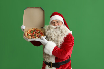 Santa Claus with box of tasty pizza on green background