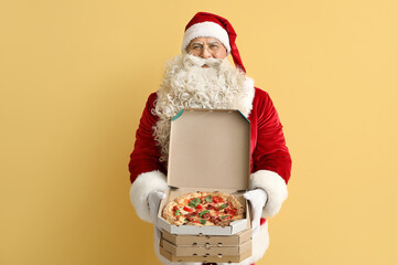 Santa Claus with boxes of tasty pizza on yellow background