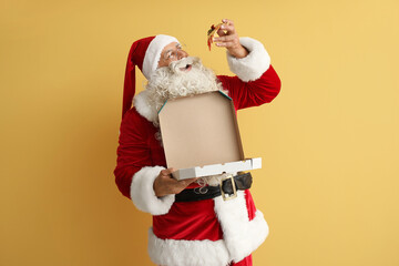Santa Claus eating tasty pizza on yellow background