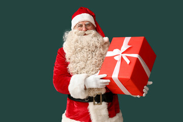 Santa Claus with Christmas gift on green background