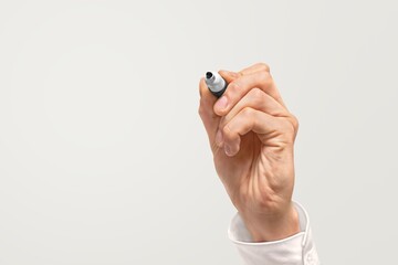 Human hand holding a pen on gray background