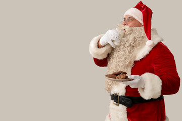 Santa Claus drinking milk with tasty cookies on white background