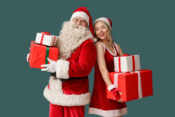 Santa Claus and beautiful woman with Christmas gifts on green background