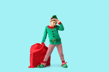 Tired little elf with bag of gifts on blue background