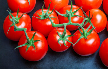 Above view studio shot of fresh tomatoes on black cutting board.	
