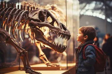Photo sur Plexiglas Vieil immeuble Child looking at the skeleton of an ancient dinosaur in the museum of paleontology. Little boy watching at dinosaur bones.