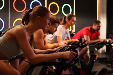 Group of people training on exercise bikes in fitness club