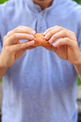 A man's hand holds a mini puff pastry with cheese, snack and fast food concept. Selective focus on hands