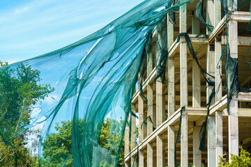 Protective mesh on scaffolding torn by hurricane wind. Background with selective focus