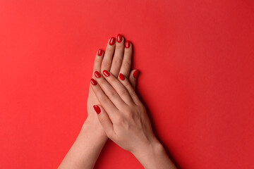 Woman with gel polish on nails against red background, top view
