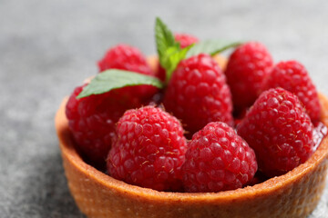 Tartlet with fresh raspberries on light grey background, closeup. Delicious dessert