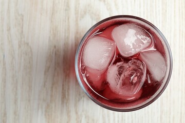 Glass of delicious iced hibiscus tea on white wooden table, top view. Space for text