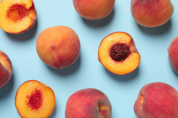 Cut and whole fresh ripe peaches on light blue background, flat lay
