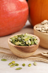 Bowls with seeds and fresh pumpkins on light wooden table